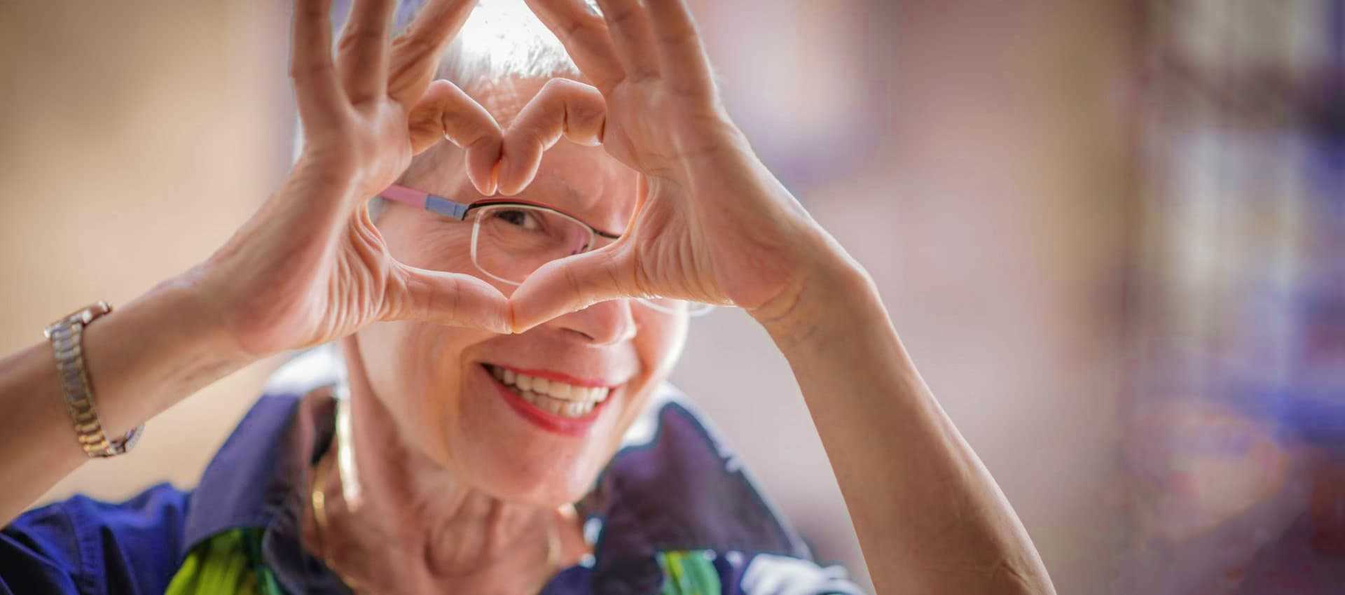 elder woman forming a heart between her fingers